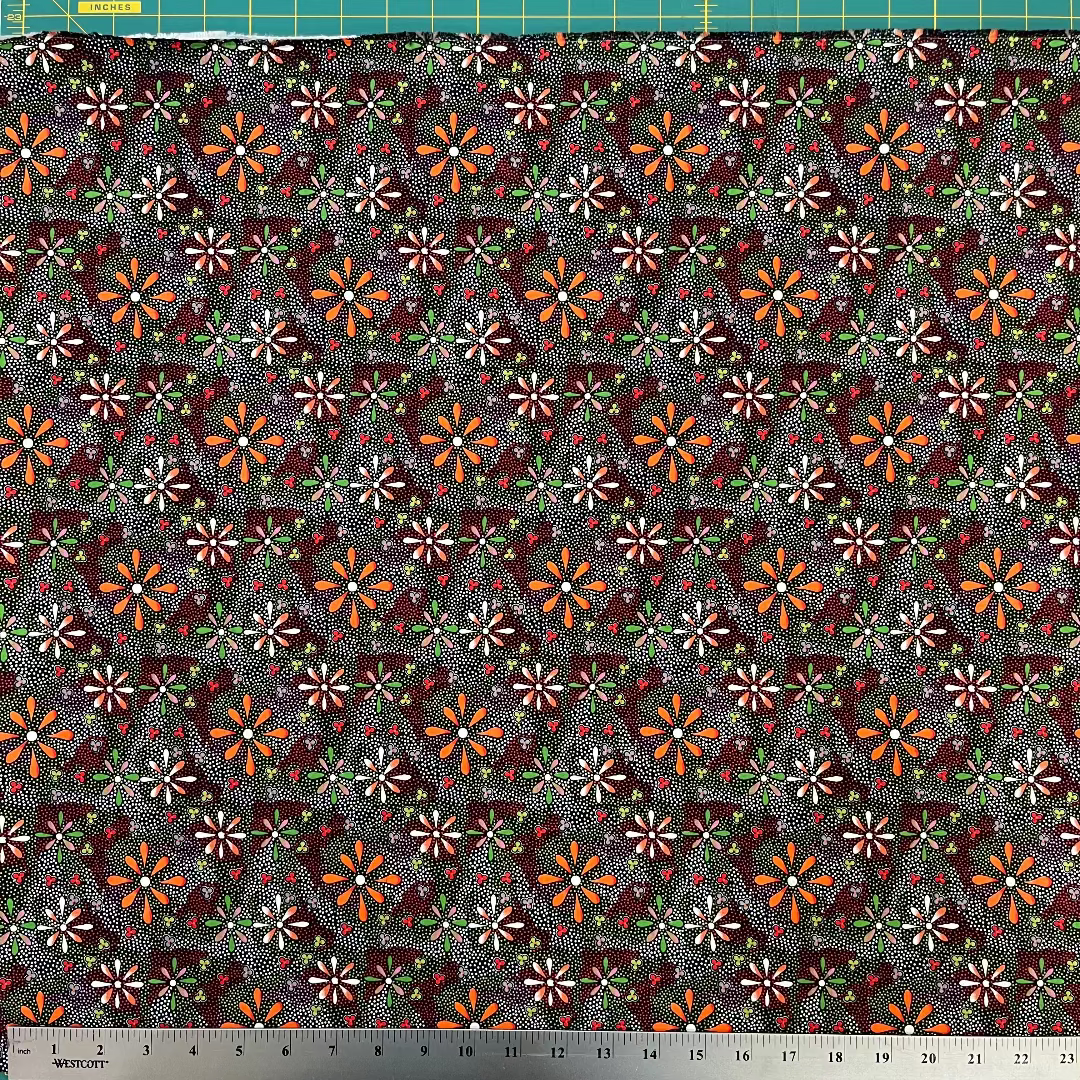Patterned fabric with small flowers on a dark background, measured with a ruler at the bottom.