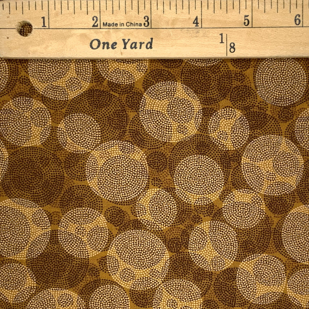 A texture design of circles formed by tiny dots in tans and browns. 