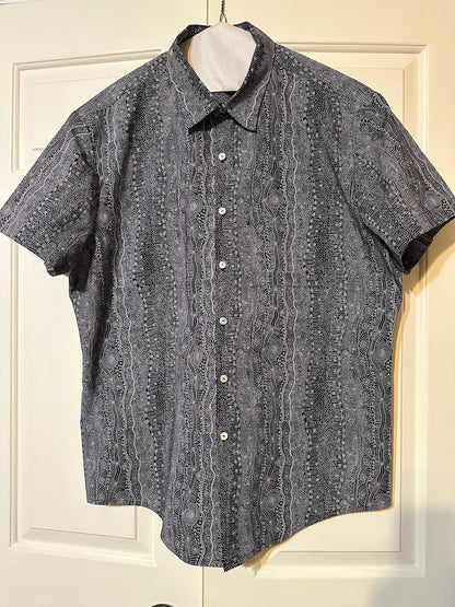 Short-sleeve hand made men's shirt with a pattern on a hanger against a white door background