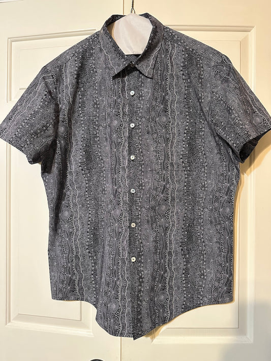 Short-sleeve hand made men's shirt with a pattern on a hanger against a white door background