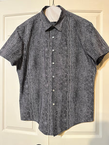 Short-sleeve hand made men's shirt with a pattern on a hanger against a white door background