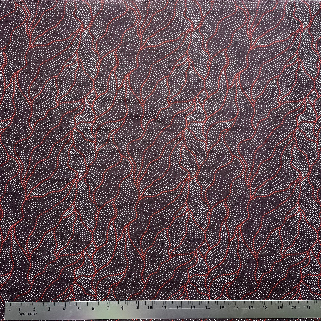 Textile with abstract pattern on a dark brown background, featuring a ruler at the bottom for scale.