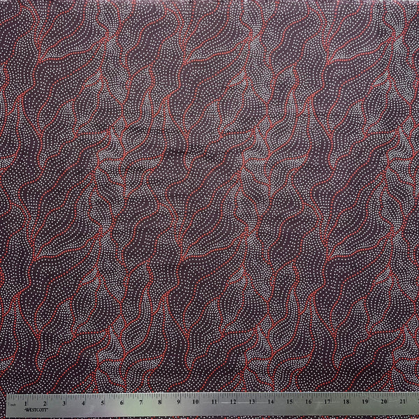 Textile with abstract pattern on a dark brown background, featuring a ruler at the bottom for scale.