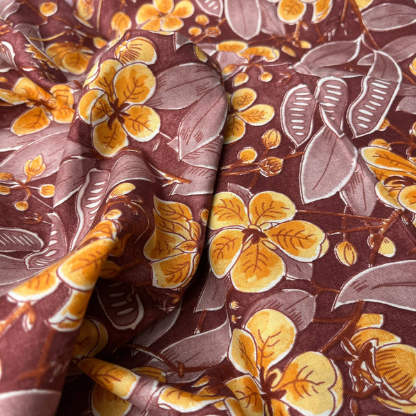 Close-up of floral fabric with yellow flowers and brown leaves on a brown background