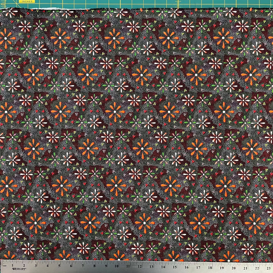 Patterned fabric with small flowers on a dark background, measured with a ruler at the bottom.