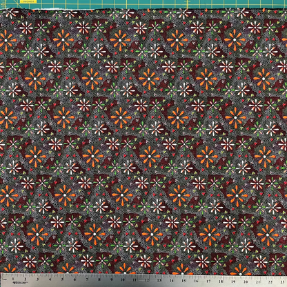 Patterned fabric with small flowers on a dark background, measured with a ruler at the bottom.
