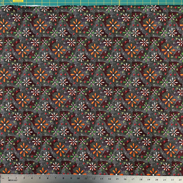 Patterned fabric with small flowers on a dark background, measured with a ruler at the bottom.