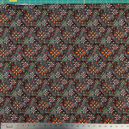 Patterned fabric with small flowers on a dark background, measured with a ruler at the bottom.