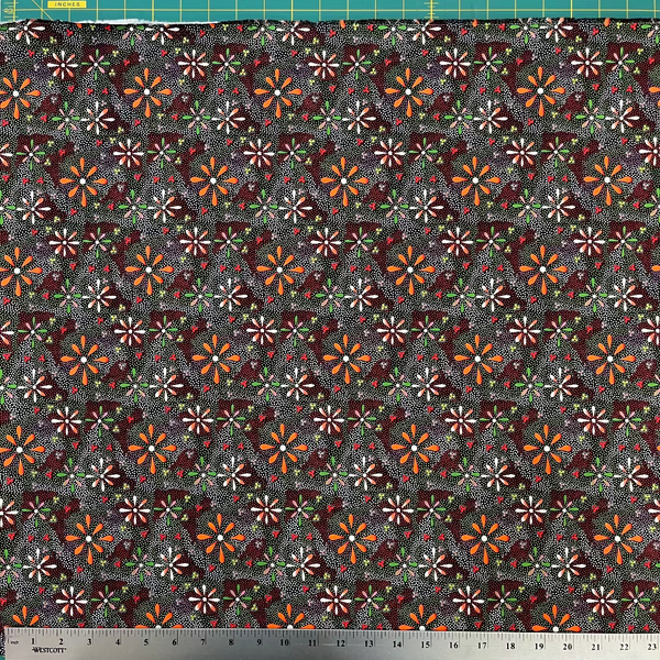 Patterned fabric with small flowers on a dark background, measured with a ruler at the bottom.