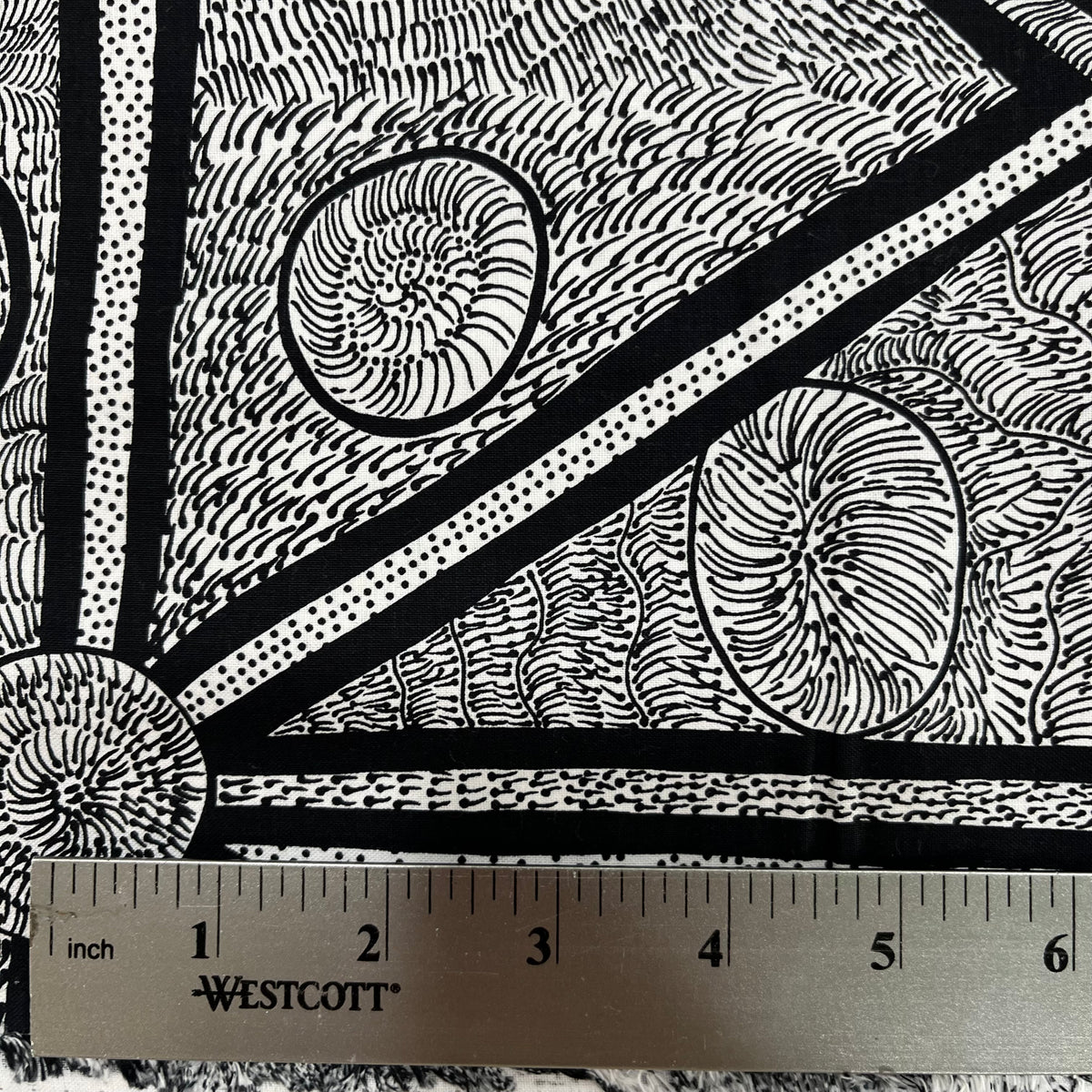 White and black fabric with abstract design, detail picture with ruler for sca;e