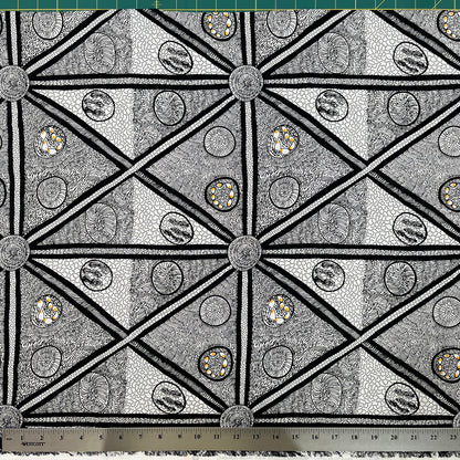 White and black fabric with abstract design, including a smidge of yellow, detail picture with ruler for scale