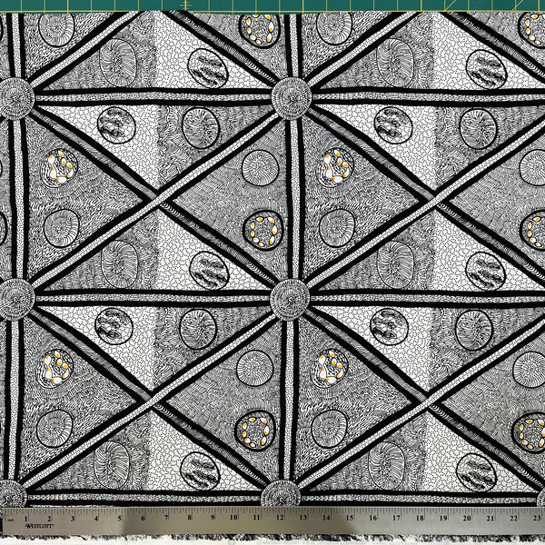 White and black fabric with abstract design, including a smidge of yellow, detail picture with ruler for scale