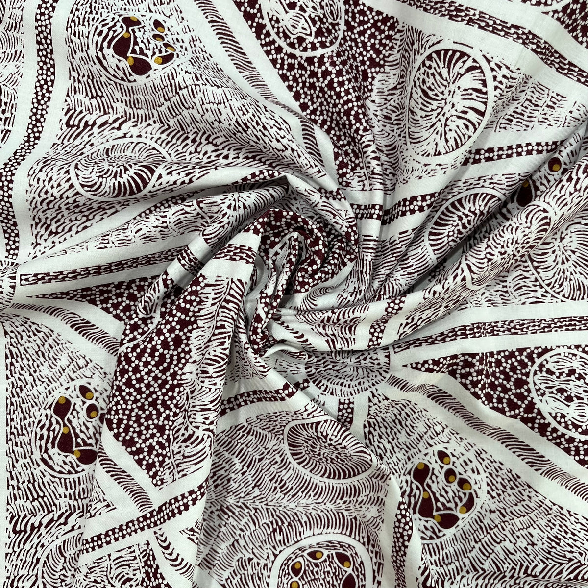 A close-up of draped fabric with an intricate white and burgundy abstract pattern featuring swirls, dots, and organic line designs.