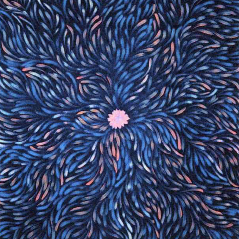 A close-up of a patterned fabric featuring a central pink flower-like motif surrounded by radiating blue, navy, and pink brushstroke lines.