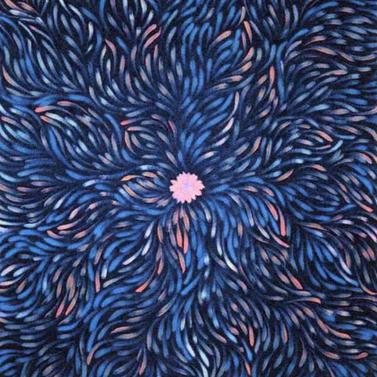 A close-up of a patterned fabric featuring a central pink flower-like motif surrounded by radiating blue, navy, and pink brushstroke lines.