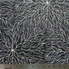 Running Water Dreaming grey is an intricate design of fine lines in white, grey and purplish grey on a black background, simulating the rivulets of water splashing from a central waterhole.
