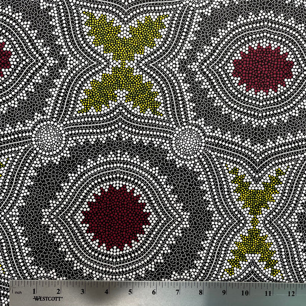 In this fabric, softly contrasting shades of grey, olive, burgundy, and white form patterns representing wind-scattered seeds and spinifex grasses—elements deeply rooted in desert life and culture.
