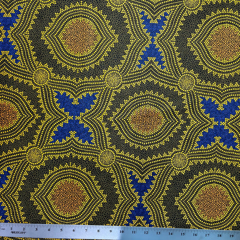 In this fabric, softly contrasting shades of gold, dark grey, blue and orange form patterns representing wind-scattered seeds and spinifex grasses—elements deeply rooted in desert life and culture.