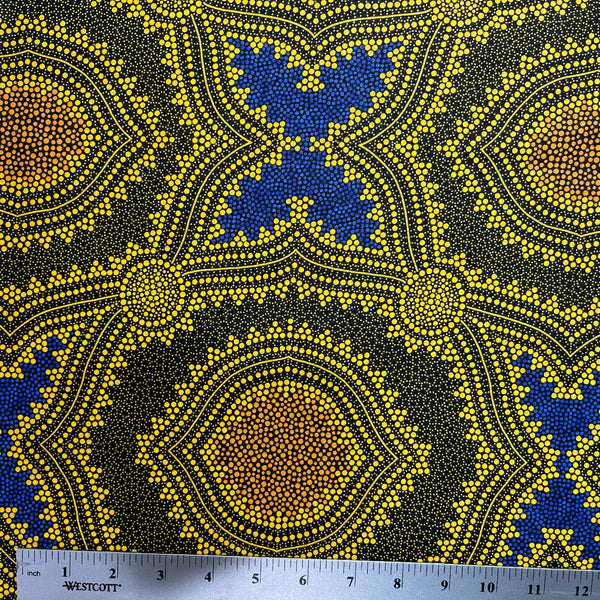 In this fabric, softly contrasting shades of gold, dark grey, blue and orange form patterns representing wind-scattered seeds and spinifex grasses—elements deeply rooted in desert life and culture.