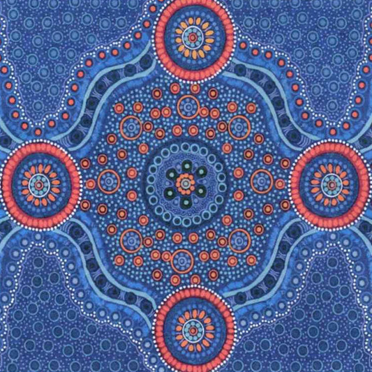 A close-up of a blue patterned fabric  featuring a central circular mandala design with coral, blue and yellow dots on a blue background