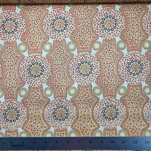Bush Flowers  ecru Australian Aboriginal fabric is an intricate design depicting flowering bushes in vivid shades of orange, red, tan and yellow on an ecru background.